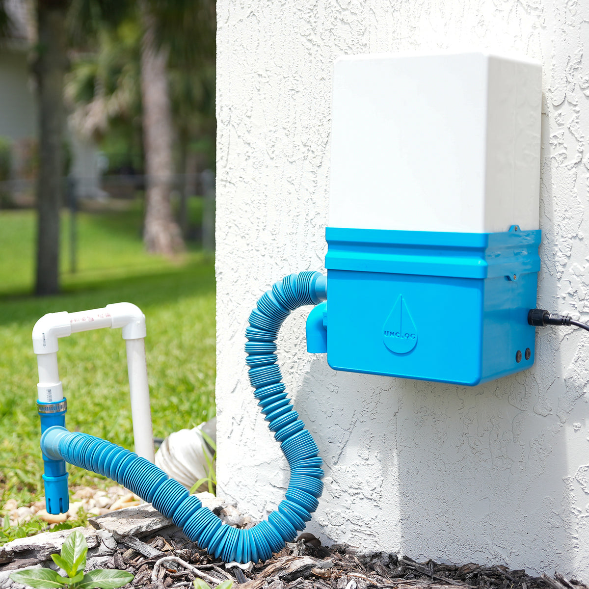 Production Unclog automatic A/C drain line cleaning system installed on a residential exterior wall
